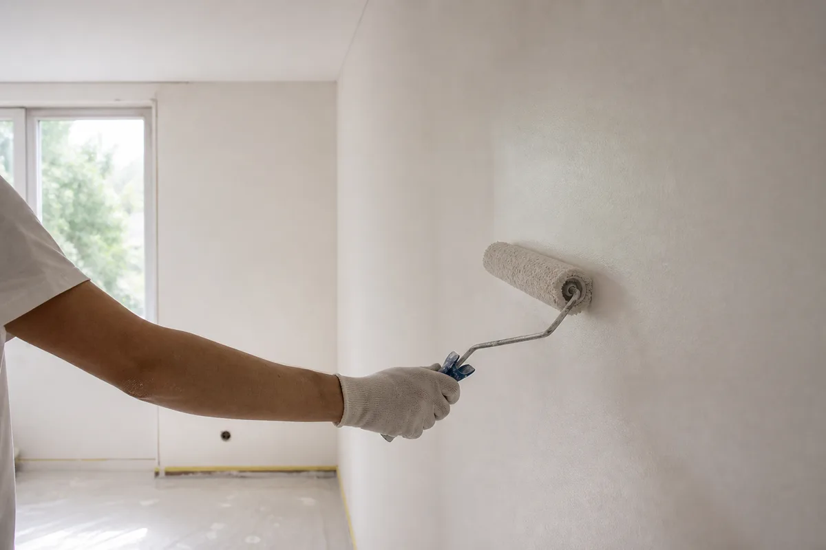 Rouleau de finition passé sur un mur clair dans une pièce vide